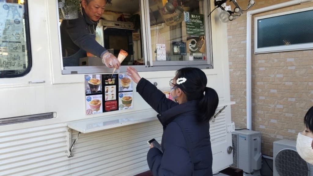 キッチンカーの窓口でクレープを受け取る様子